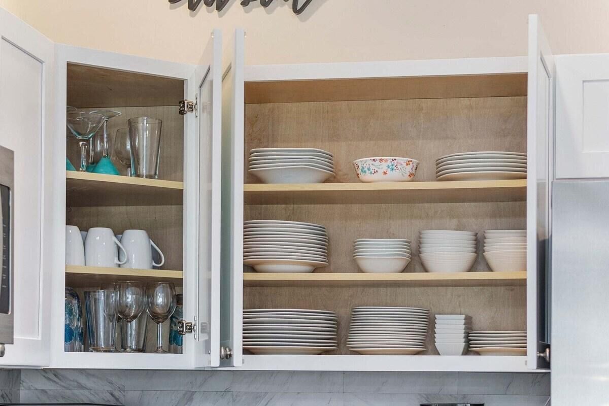 A kitchen cabinet with multiple shelves holding various dishes and glassware.