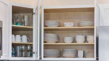 A kitchen cabinet with multiple shelves holding various dishes and glassware.