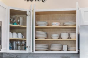 A kitchen cabinet with multiple shelves holding various dishes and glassware. - Sunshine Derby-1 Block to Beach-garage EV Charger (Myrtle Beach)
