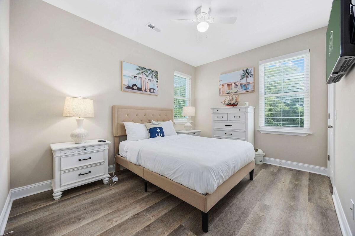 A bedroom with a bed, nightstands, a ceiling fan, and artwork on the walls.