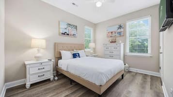 A bedroom with a bed, nightstands, a ceiling fan, and artwork on the walls.