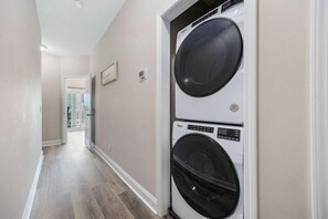 A laundry room with two stacked front-loading washing machines. - Sunshine Derby-1 Block to Beach-garage EV Charger (Myrtle Beach)