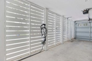 A garage with white sliding doors and a concrete floor. - Sunshine Derby-1 Block to Beach-garage EV Charger (Myrtle Beach)