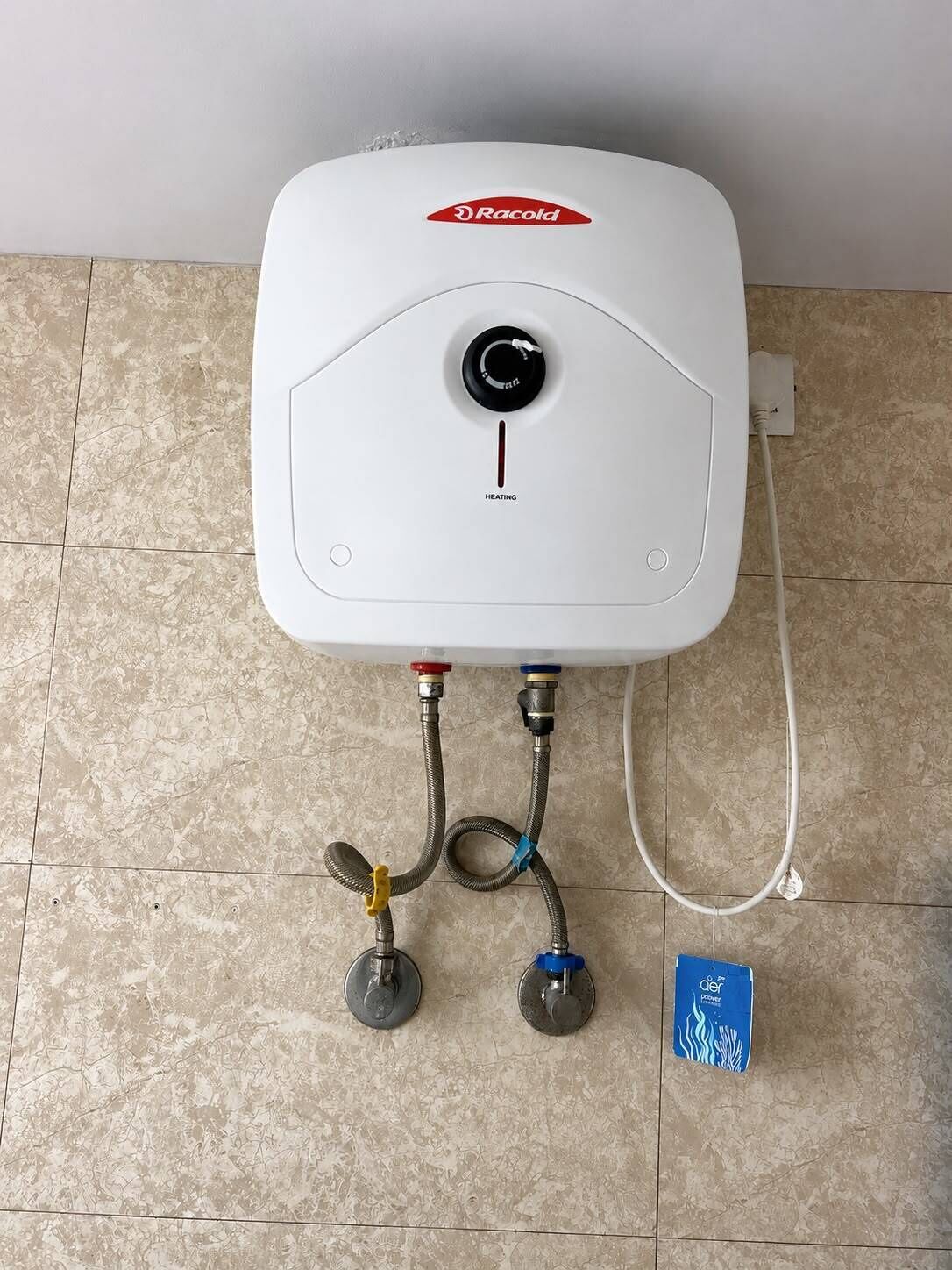 A white water heater with a control knob, two valves, and a power cord.