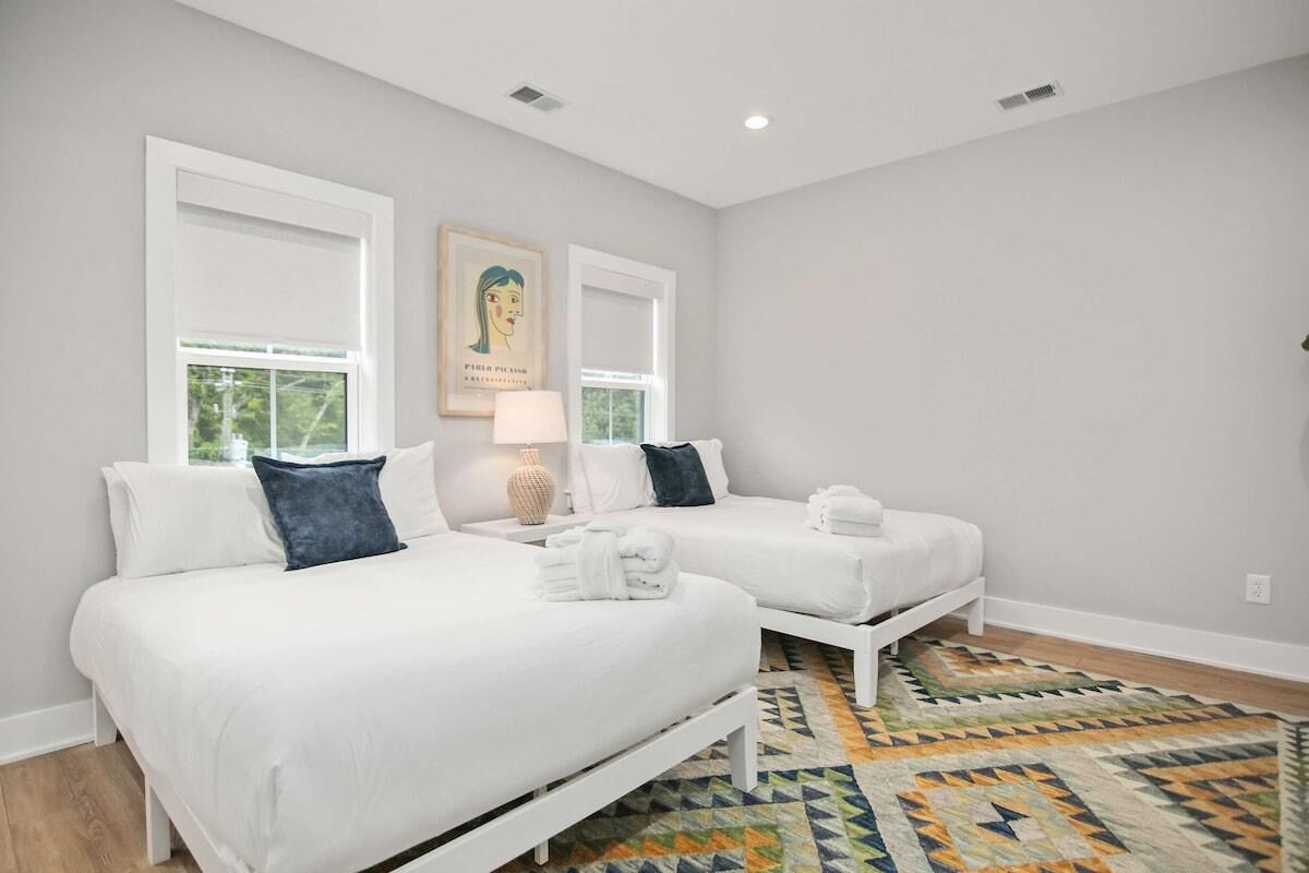 A hotel room with two beds, a patterned rug, and a painting on the wall.