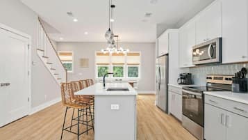 A modern kitchen with white cabinetry, stainless steel appliances, and a central island with bar stools.