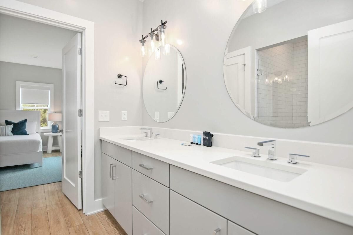 A modern bathroom with a large mirror, two sinks, and a walk-in shower.
