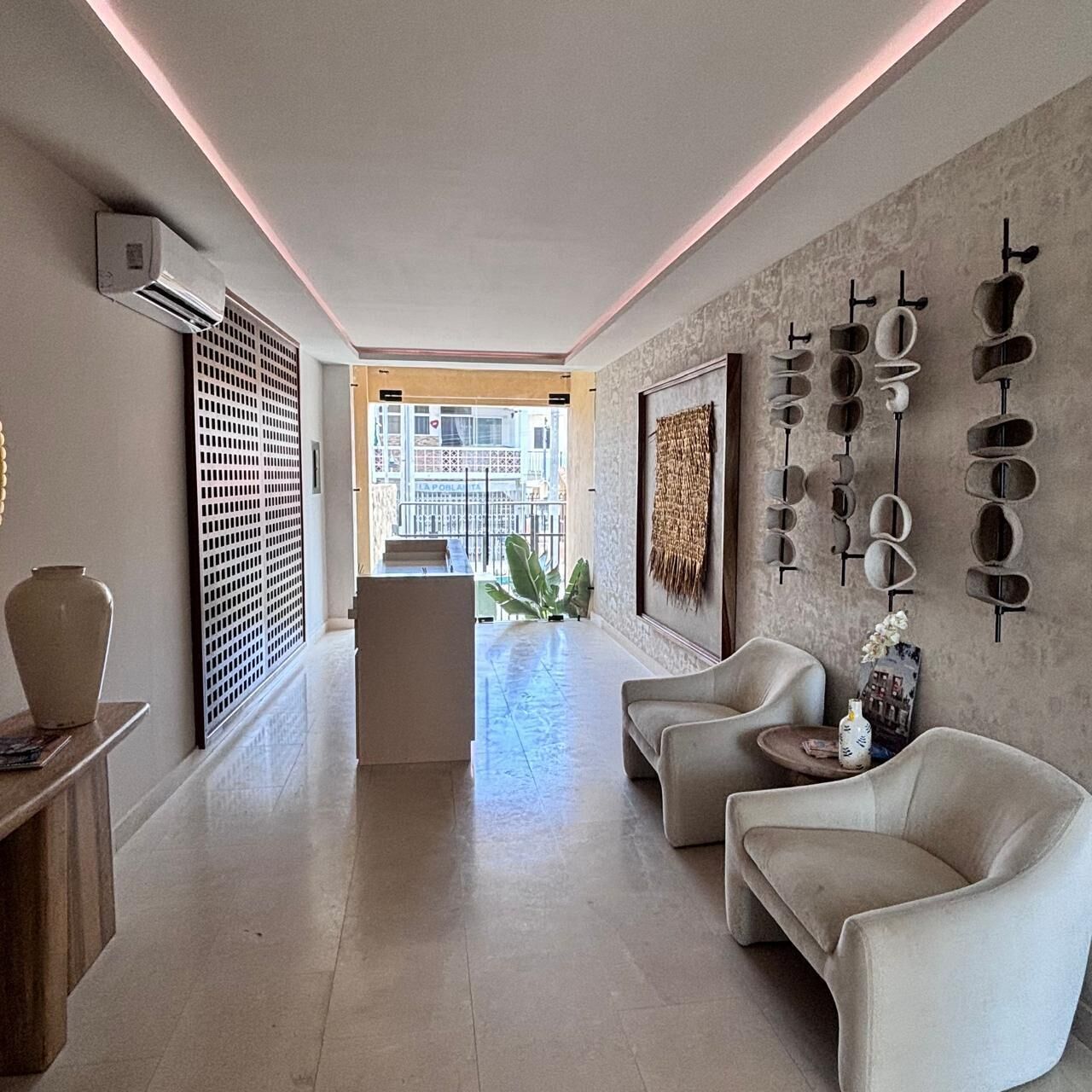 A modern interior with a seating area, a decorative wall, and a view to the outside.