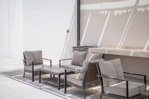 An outdoor seating area with a sofa and chairs, a small table, and a window with a view. - Cabo Studio 13. Three blocks away from the Marina. (Cabo San Lucas)