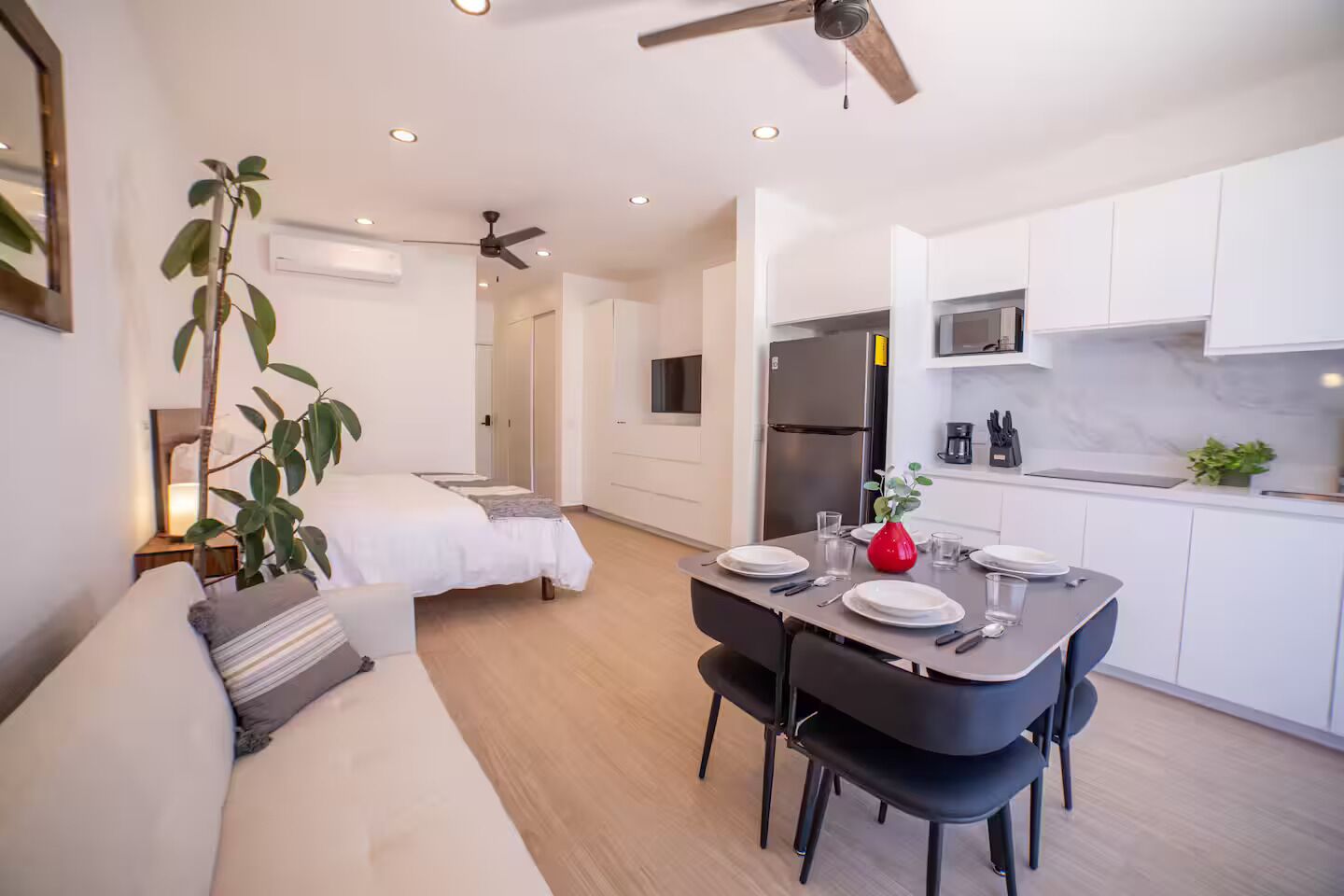 Een modern appartement met een eethoek, een keuken, een woonkamer met een bank en een plafondventilator.
