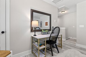 Quarto moderno com escrivaninha, cadeira e um espelho grande.