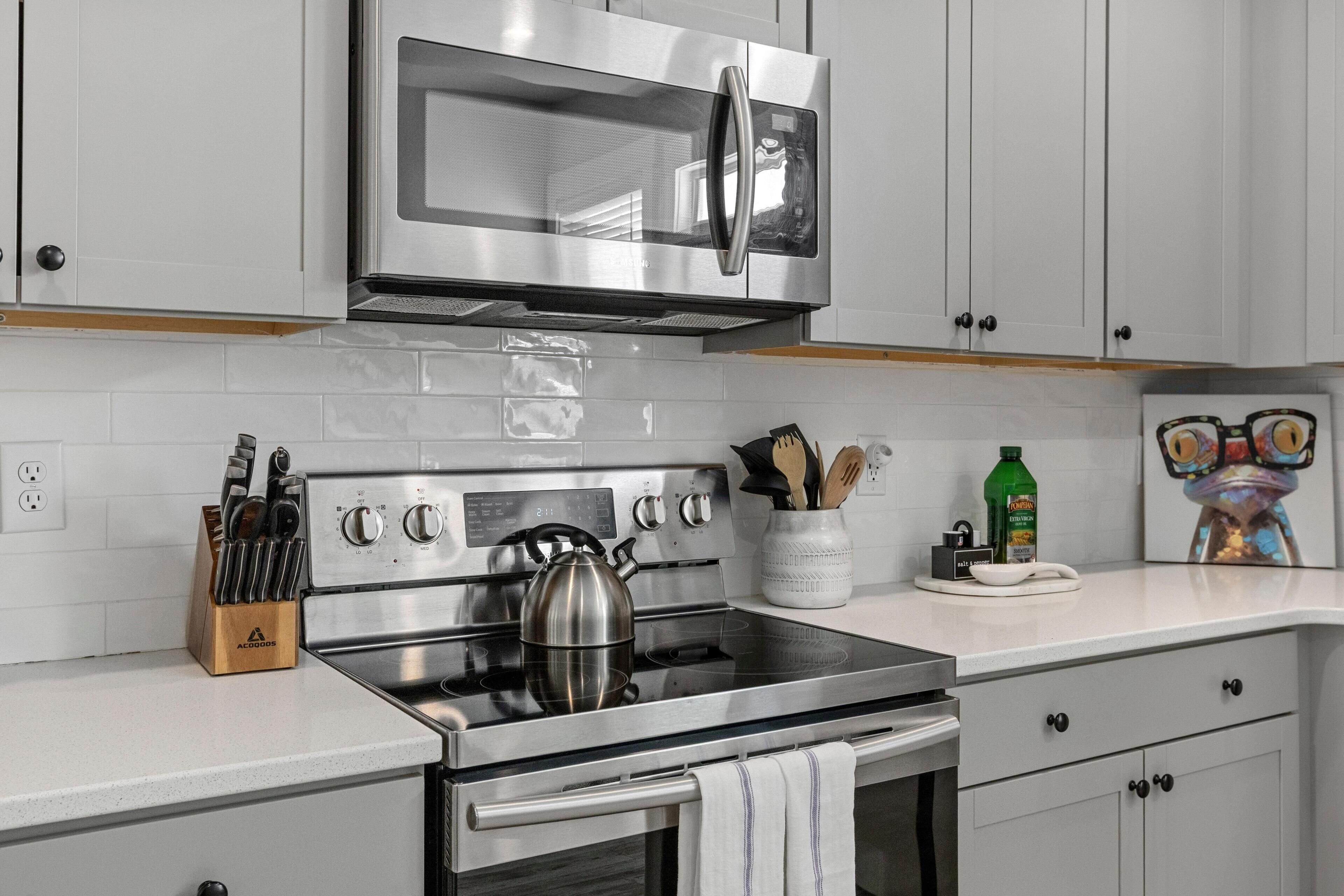 A modern kitchen with stainless steel appliances, a kettle, and a knife block.