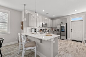 A modern kitchen with white cabinetry, stainless steel appliances, and a central island with seating. - Creekside Bungalow-park Circle-15m Dtwn CHS (North Charleston)