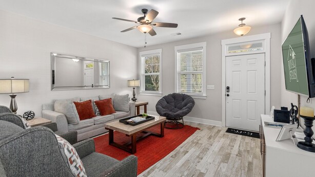 A living room with a sofa, armchair, coffee table, and a ceiling fan. - Creekside Bungalow-park Circle-15m Dtwn CHS (North Charleston)