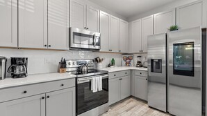 A modern kitchen with white cabinets, stainless steel appliances, and a built-in microwave. - Creekside Bungalow-park Circle-15m Dtwn CHS (North Charleston)