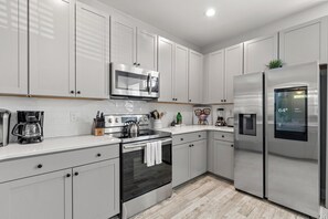A modern kitchen with white cabinets, stainless steel appliances, and a built-in microwave. - Creekside Bungalow-park Circle-15m Dtwn CHS (North Charleston)