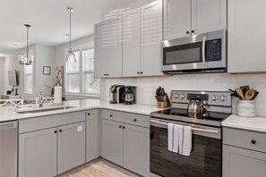 A modern kitchen with grey cabinets, stainless steel appliances, a built-in oven, and a microwave. - Creekside Bungalow-park Circle-15m Dtwn CHS (North Charleston)