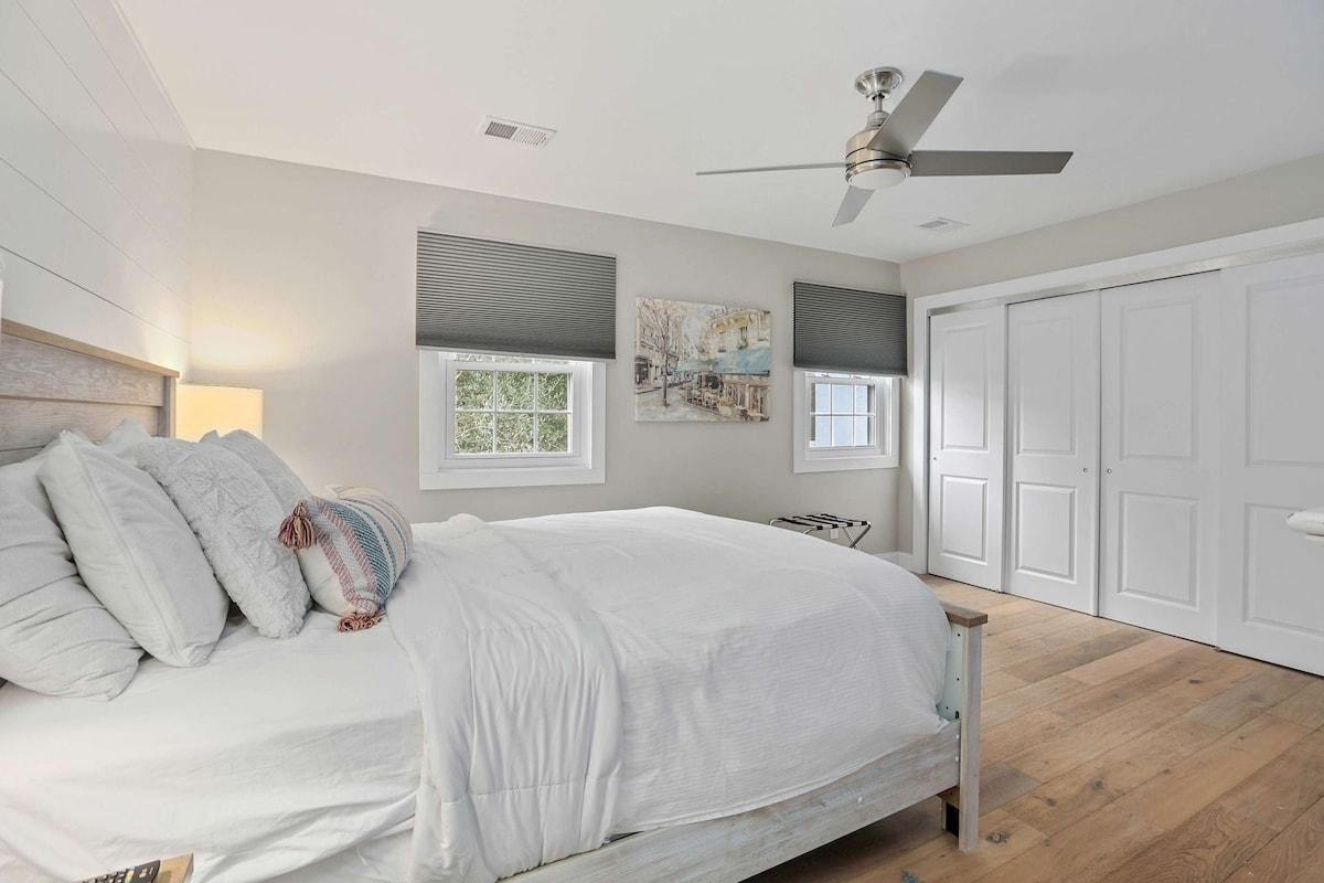 Una camera da letto con un letto, una ventola a soffitto, una finestra e una porta.