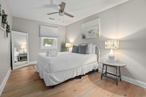 A bedroom with a bed, bedside lamps, a ceiling fan, a window with blinds, and a mirror. - Coastal Casa-old Village-5 Mins to Beach (Mount Pleasant)