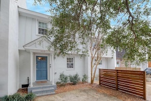 A white two-story house with a blue door and a number 955 on the front.