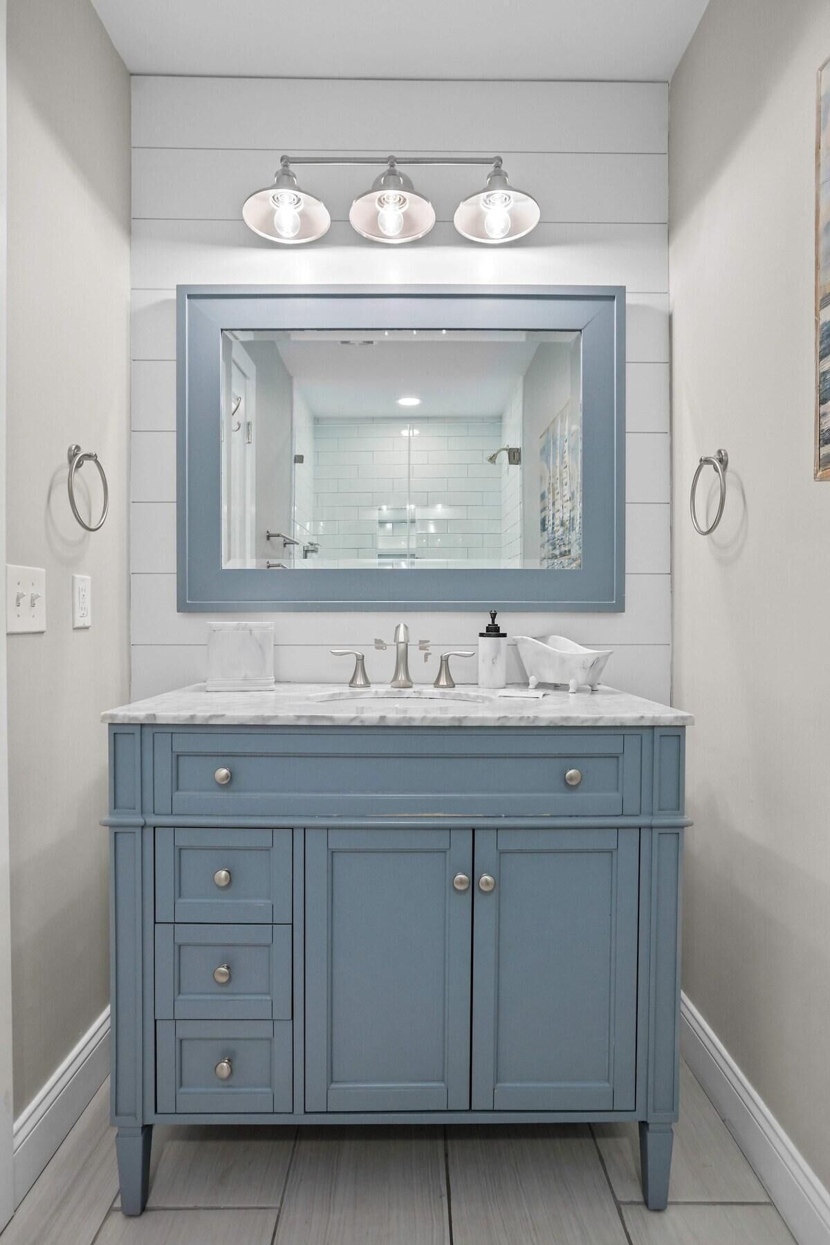 A bathroom with a large vanity, a mirror, and three wall-mounted lights.