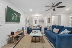 A living room with a blue sofa, a coffee table, and a TV mounted on the wall.