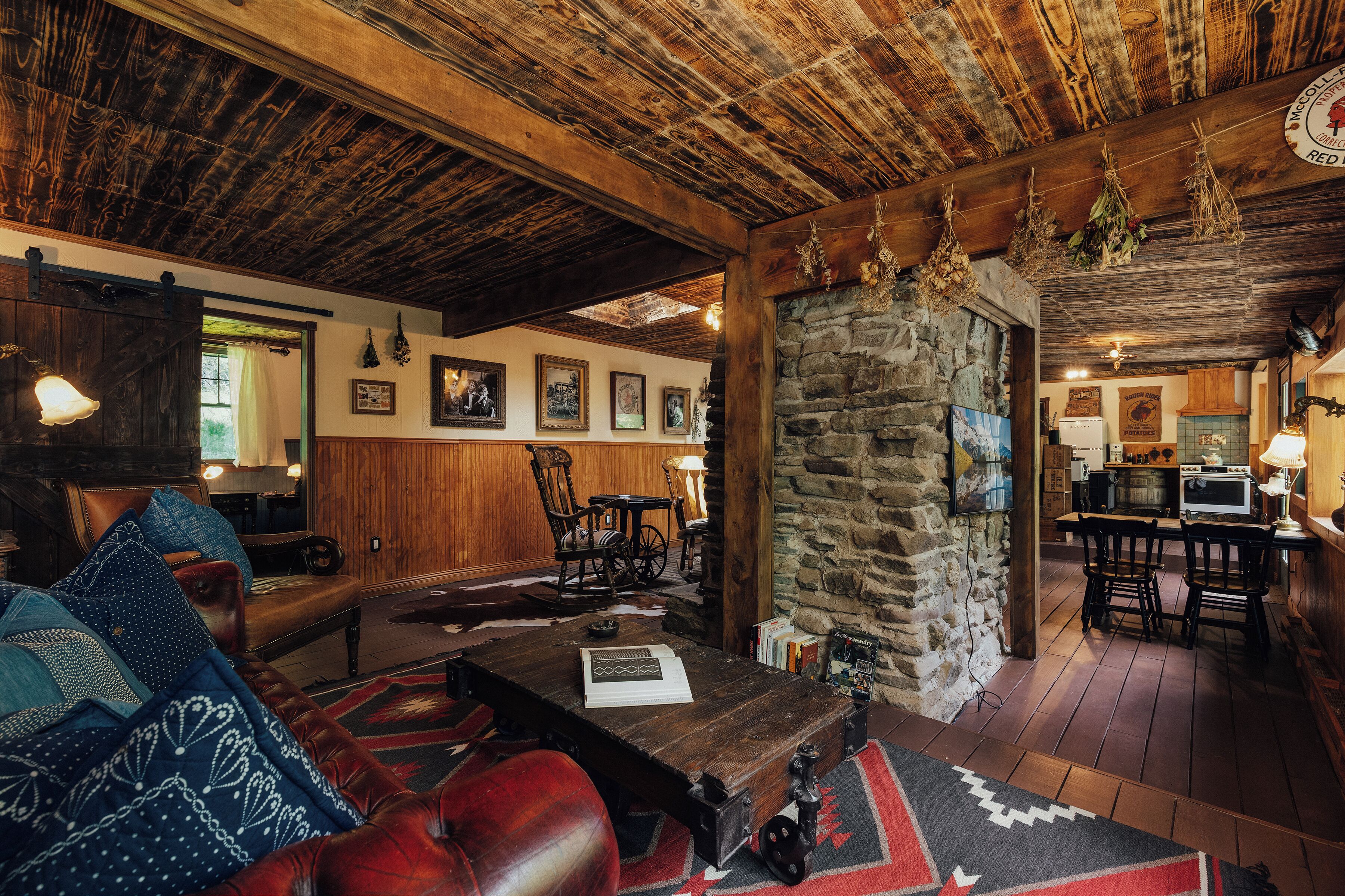 A rustic interior with a wooden ceiling, stone wall, and a cozy seating area with a leather sofa and a coffee table.