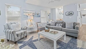 A modern living room with a striped armchair, a grey sofa, a white coffee table, and a blue patterned rug. - The Costal Haven - 5 Min Beach, 15 Min to DT (Mount Pleasant)