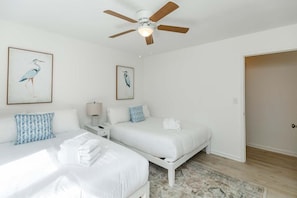 A hotel room with two beds, a ceiling fan, and artwork of birds on the walls. - Southern Serenity, Fenced in Yard, Pet Friendly (Mount Pleasant)