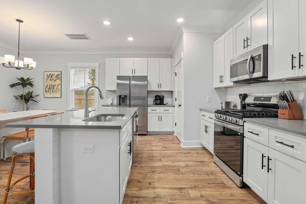 A modern kitchen with white cabinetry, stainless steel appliances, and a central island.