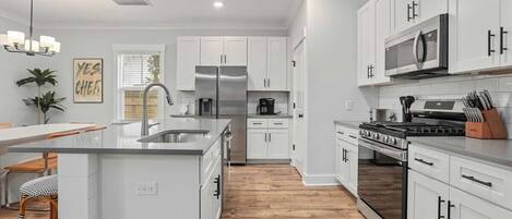 A modern kitchen with white cabinetry, stainless steel appliances, and a central island.