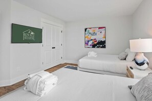 Habitación de hotel con cama, mesita de noche con lámpara, televisor montado en la pared y una puerta.