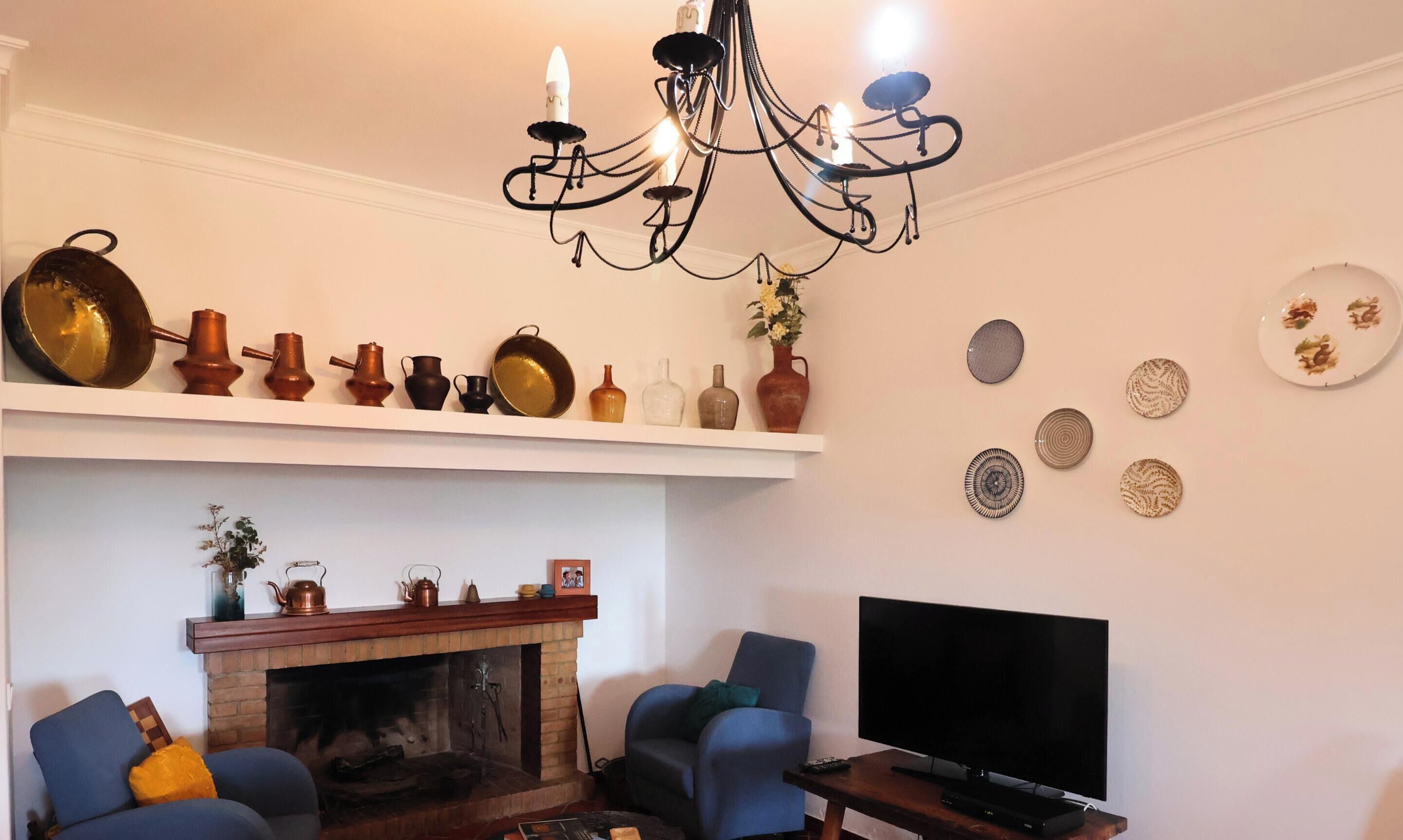 A living room with a fireplace, a television, and a chandelier.