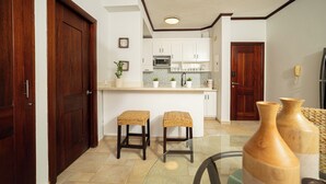 A modern kitchen with white cabinets, a microwave, and two wicker stools. - Bright & Moderm 2BR/Aparment Comfort & Style  (Cabarete)