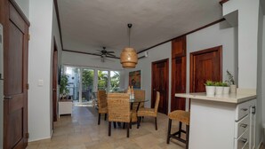 A spacious dining area with wicker chairs, a ceiling fan, and a white cabinet with potted plants. - Bright & Moderm 2BR/Aparment Comfort & Style  (Cabarete)