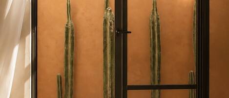 A room with a sliding glass door, a view of the sky, and three potted cacti.