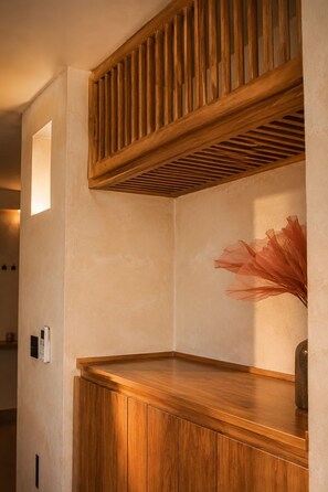 A corner of a room with a wooden bench, a wall-mounted light fixture, and a decorative vase. - Your Plum Tree (La Paz)