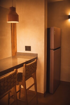 Eine Küche mit modernem Design, ausgestattet mit einem Einbaukühlschrank, einer Holzbar und zwei Korbstühlen.