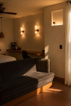 Ein modernes Hotelzimmer mit einer Sitzecke, einem kleinen Tisch mit Kaffeemaschine und zwei Wandleuchten.