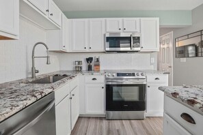 A modern kitchen with white cabinets, a stainless steel oven, a microwave, and a granite countertop. - Chucktown Charm- 8 Mins to Credit One (Charleston)