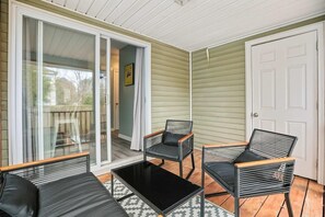 A covered patio with two black wicker chairs and a black table, a sliding glass door, and a white door. - Chucktown Charm- 8 Mins to Credit One (Charleston)