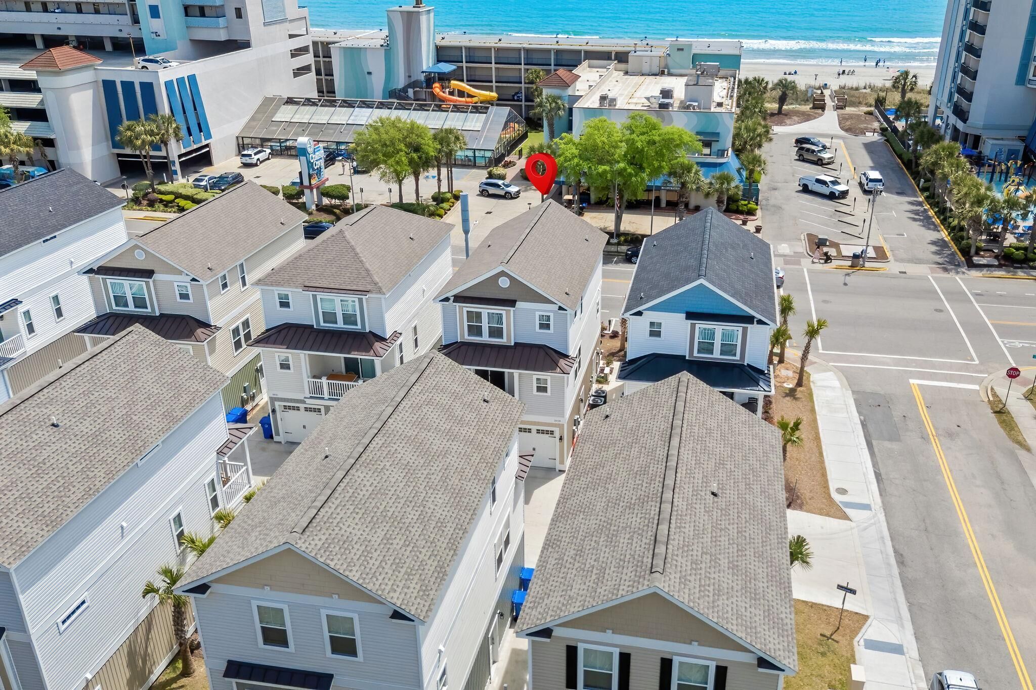 A residential area with houses, a parking lot, and a beach in the background.