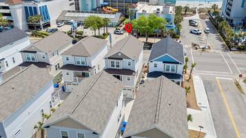 A residential area with houses, a parking lot, and a beach in the background.