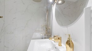 A bathroom with a white sink, gold fixtures, a handheld showerhead, and a large mirror. - Studio Apartment 'Cosy and Central' with Wi-Fi and Air Conditioning (Nice)
