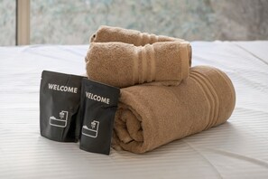 A neatly made bed with a rolled towel and two welcome bags on a white bedspread. - Studio Apartment 'Cosy and Central' with Wi-Fi and Air Conditioning (Nice)
