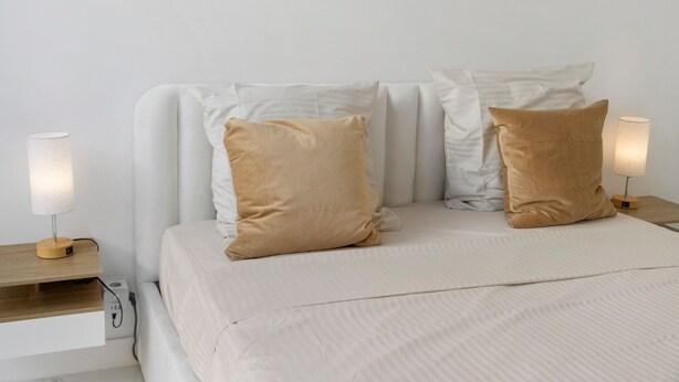A bed with two beige pillows, a white headboard, and two bedside lamps on wooden nightstands. - Studio Apartment 'Cosy and Central' with Wi-Fi and Air Conditioning (Nice)