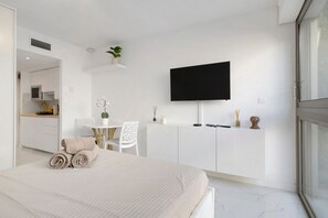 Una habitación de hotel moderna con cama, escritorio, televisión y kitchenette.