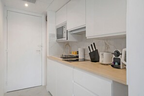 A modern kitchen with white cabinetry, a microwave, a coffee machine, and a toaster. - Studio Apartment 'Cosy and Central' with Wi-Fi and Air Conditioning (Nice)