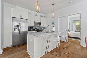 Una cocina moderna con armarios blancos, electrodomésticos de acero inoxidable y una isla central con taburetes de bar.