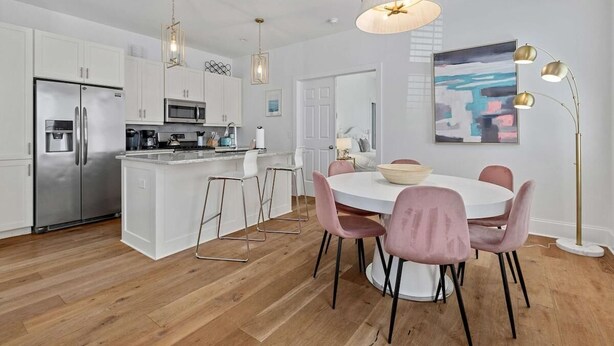 Una cocina moderna con armarios blancos, electrodomésticos de acero inoxidable y una isla central con taburetes de bar.